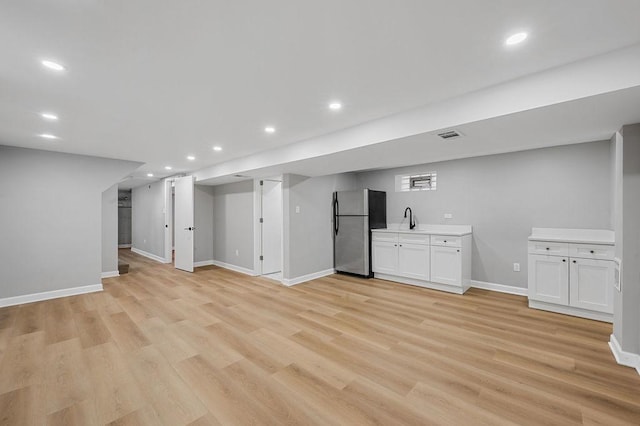 finished basement with a sink, light wood-style flooring, recessed lighting, and freestanding refrigerator
