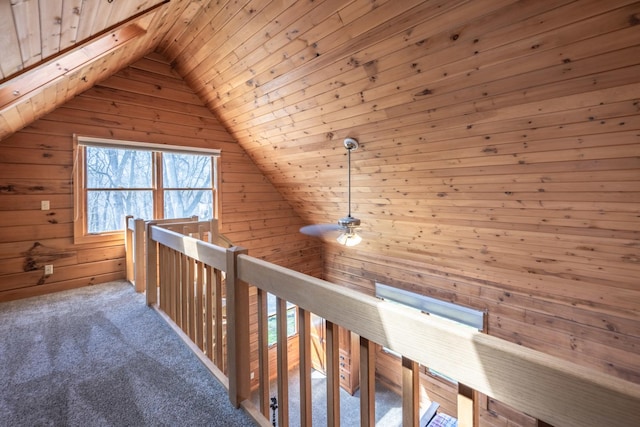 hallway with vaulted ceiling, an upstairs landing, carpet floors, wooden ceiling, and wood walls