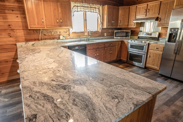 kitchen with stainless steel appliances, a peninsula, under cabinet range hood, and light stone counters