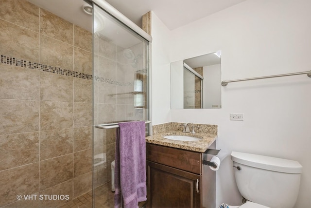 bathroom with a stall shower, toilet, and vanity