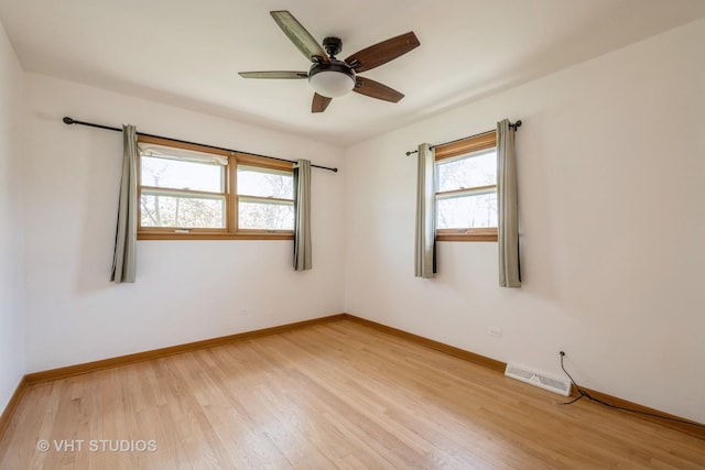 spare room with healthy amount of natural light, light wood-style floors, and baseboards