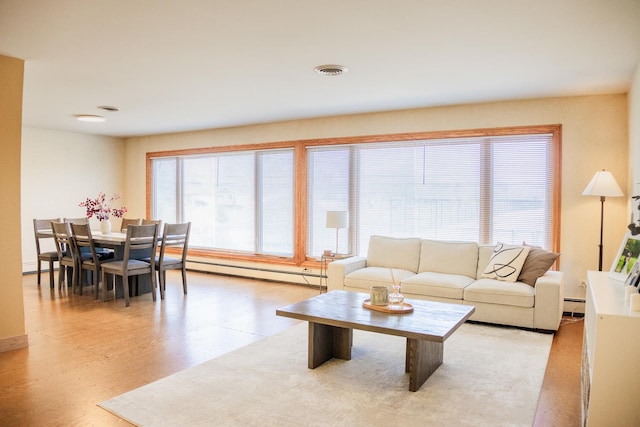 living room with visible vents, a baseboard heating unit, and light wood-type flooring