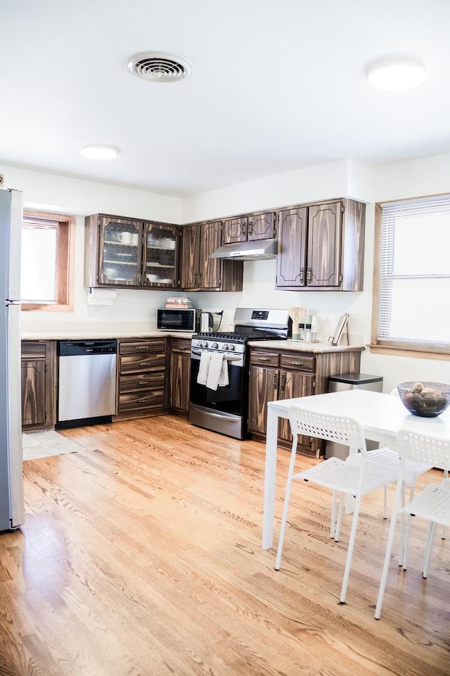 kitchen featuring light wood finished floors, visible vents, dark brown cabinetry, and stainless steel appliances