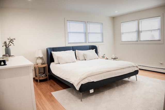 bedroom featuring light wood finished floors and baseboard heating