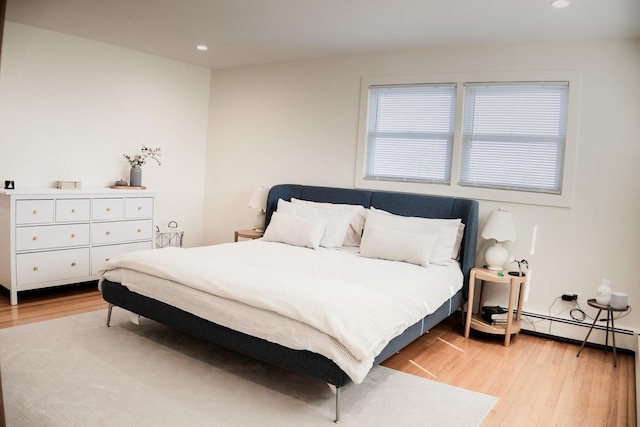 bedroom featuring a baseboard radiator, recessed lighting, and light wood-type flooring