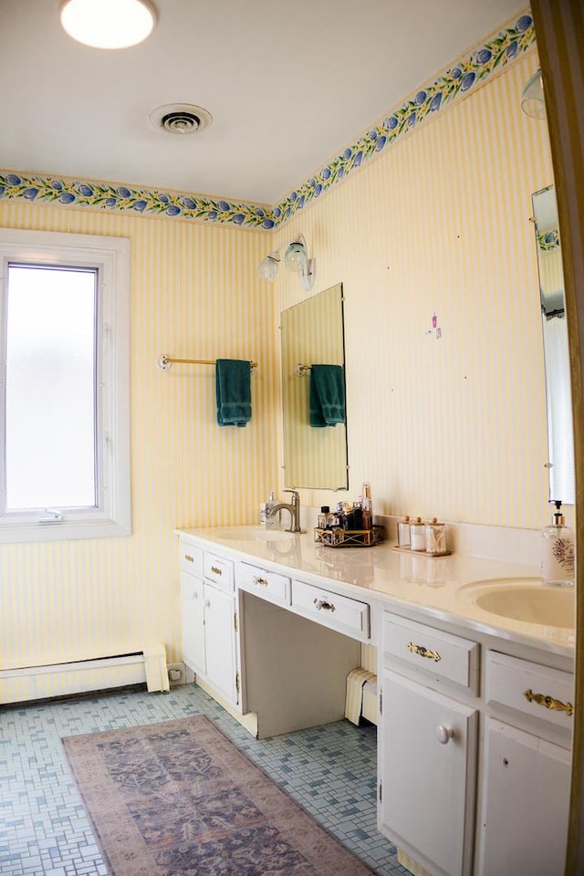 full bath with a sink, double vanity, visible vents, and a baseboard heating unit