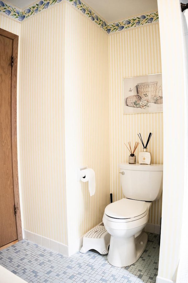 bathroom featuring baseboards, wallpapered walls, toilet, and tile patterned flooring
