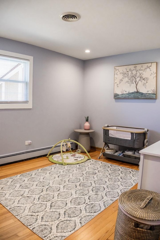 bedroom featuring visible vents, wood finished floors, a baseboard heating unit, and recessed lighting