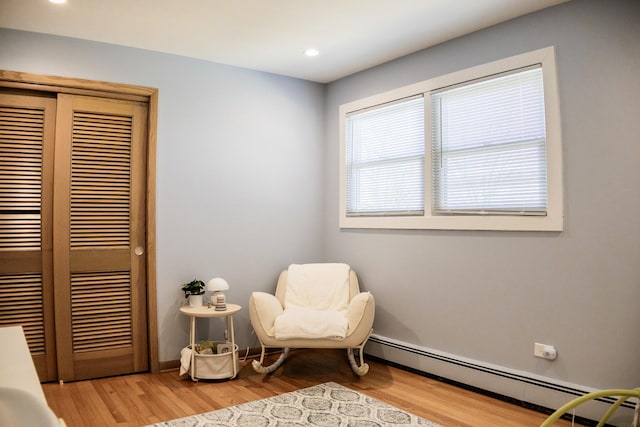 sitting room featuring a baseboard radiator, light wood-style floors, baseboards, and recessed lighting