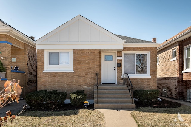 bungalow-style home with board and batten siding, brick siding, and roof with shingles