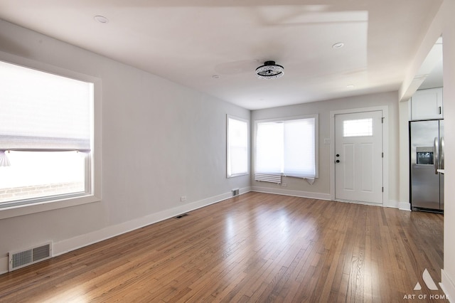 foyer featuring wood-type flooring, baseboards, and visible vents