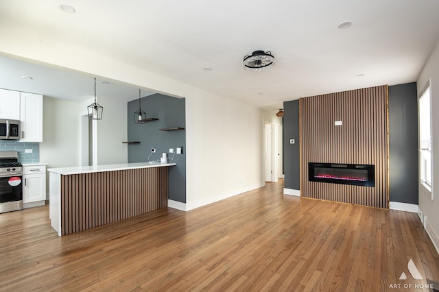 kitchen with white cabinetry, light wood-style flooring, appliances with stainless steel finishes, and backsplash