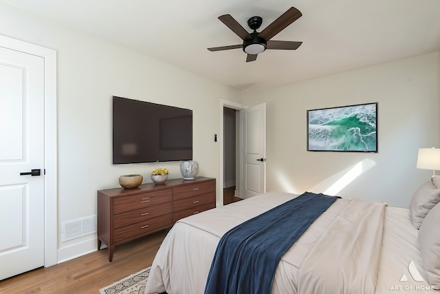 bedroom with light wood-type flooring, a ceiling fan, baseboards, and visible vents