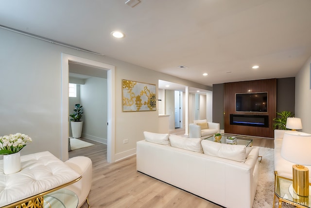 living room featuring baseboards, visible vents, light wood-style flooring, and recessed lighting