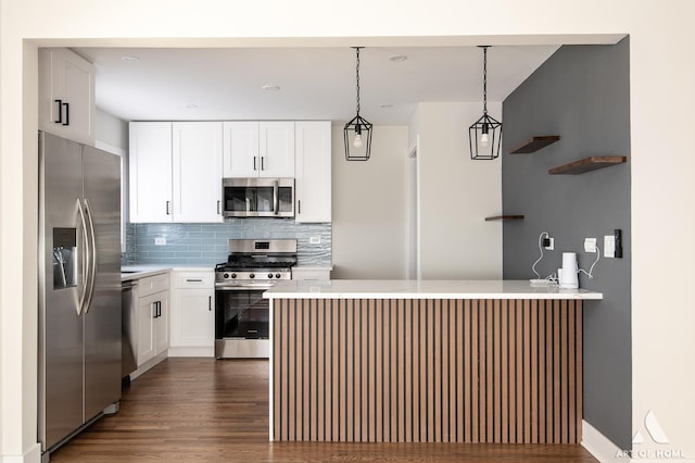 kitchen featuring light countertops, dark wood-type flooring, backsplash, a peninsula, and appliances with stainless steel finishes