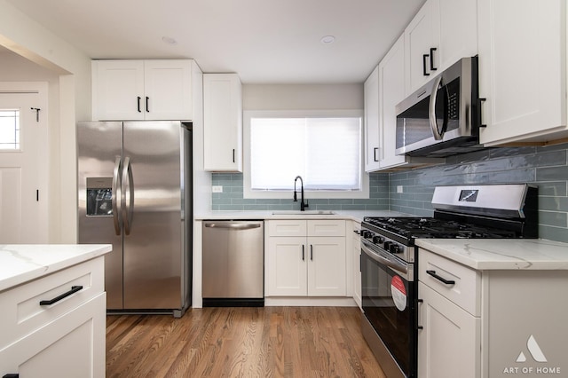 kitchen with white cabinets, a sink, stainless steel appliances, and light wood-type flooring