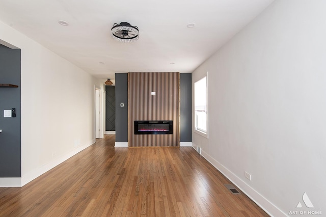 unfurnished living room with baseboards, a fireplace, and wood finished floors