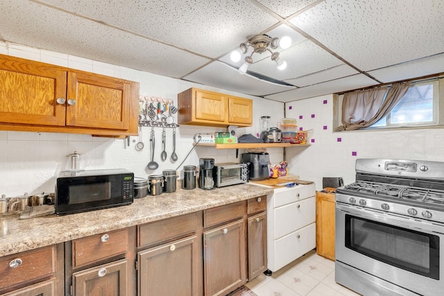 kitchen featuring open shelves, gas stove, a drop ceiling, black microwave, and brown cabinetry