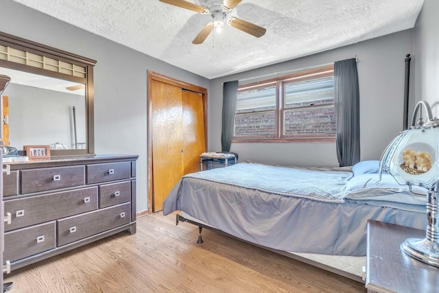bedroom featuring ceiling fan, a closet, light wood finished floors, and a textured ceiling
