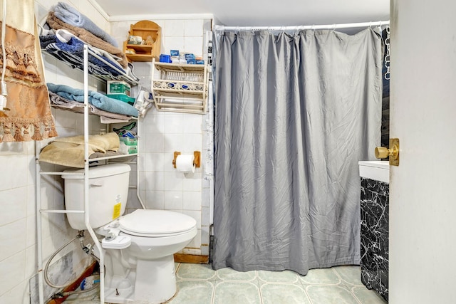 bathroom with toilet, curtained shower, tile patterned flooring, and tile walls