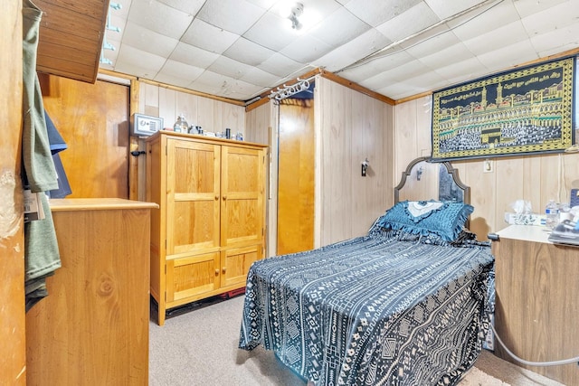 bedroom with wooden walls and light carpet