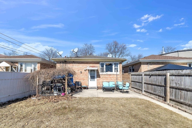 rear view of house with brick siding, a fenced backyard, and a patio area