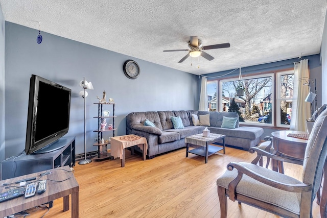 living room featuring a ceiling fan, light wood finished floors, and a textured ceiling
