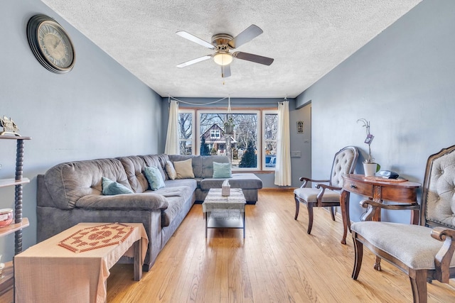 living room with a textured ceiling, light wood-type flooring, and a ceiling fan