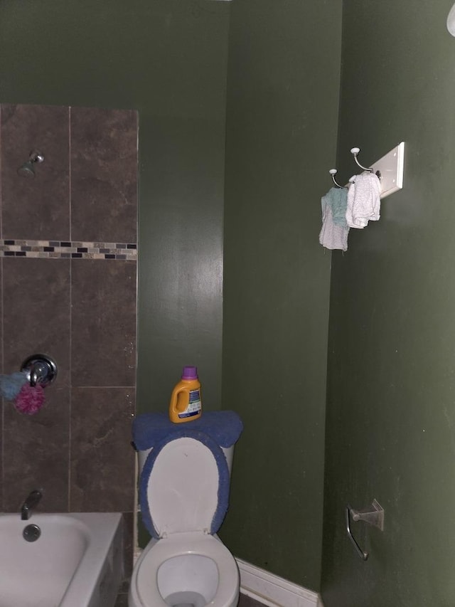 bathroom with baseboards,  shower combination, and toilet