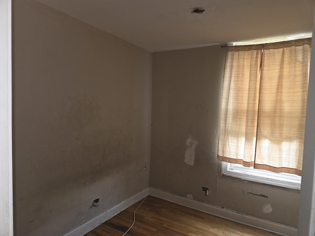 spare room featuring baseboards and wood finished floors