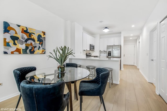 dining space with light wood finished floors, baseboards, and recessed lighting