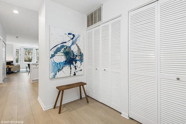 hallway featuring recessed lighting, visible vents, baseboards, and light wood-style flooring