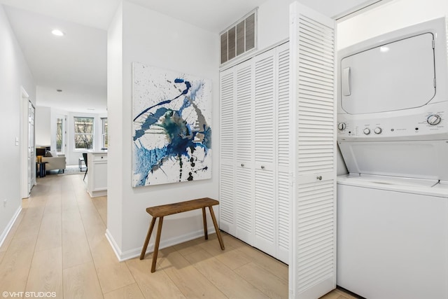 washroom with visible vents, baseboards, stacked washer / dryer, laundry area, and light wood-style flooring