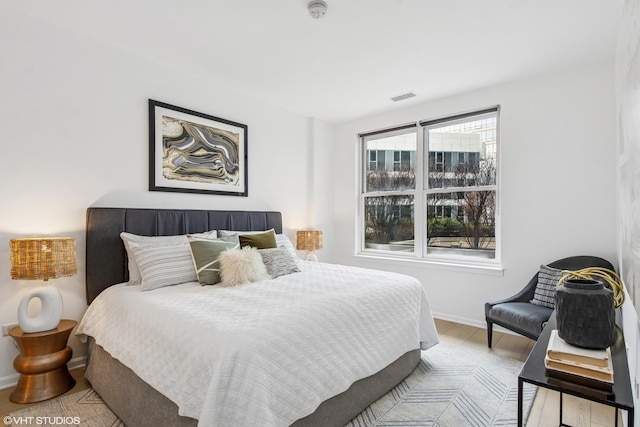 bedroom with wood finished floors, baseboards, and visible vents