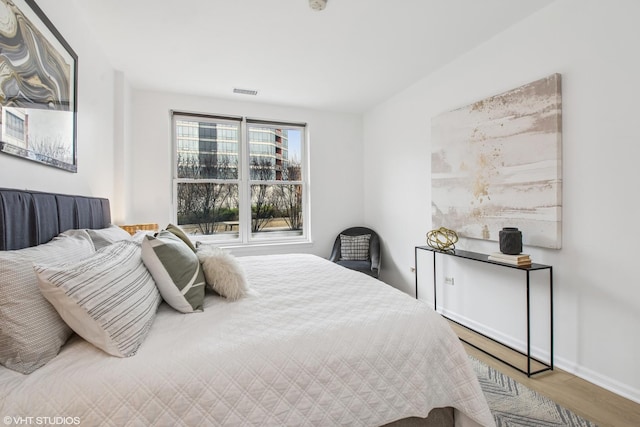 bedroom featuring visible vents, baseboards, and wood finished floors