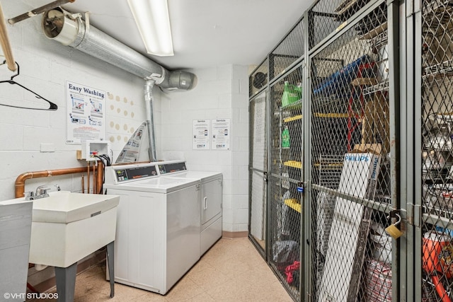 community laundry room featuring washing machine and dryer, concrete block wall, and light flooring