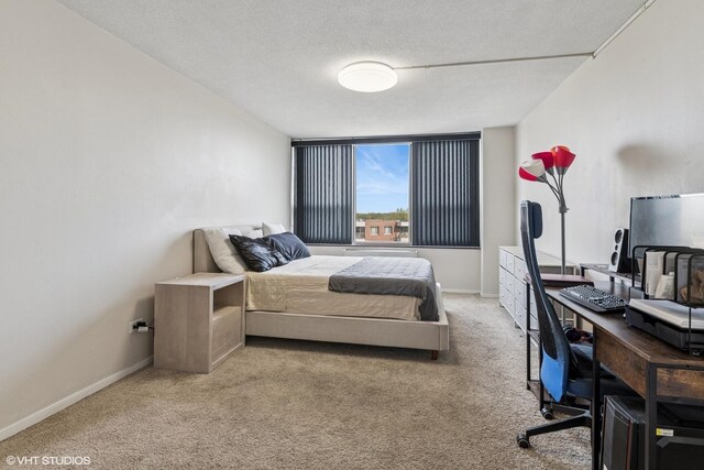 carpeted bedroom featuring an office area, baseboards, and a textured ceiling