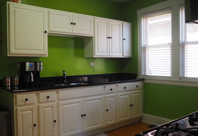 3005 N Kostner Ave, Chicago, IL 60641 - kitchen with baseboards, wood finished floors, a sink, and white cabinets