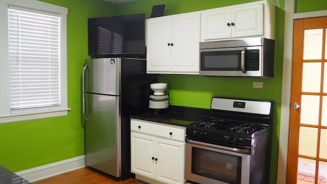 3005 N Kostner Ave, Chicago, IL 60641 - kitchen with stainless steel appliances, white cabinetry, baseboards, and wood finished floors