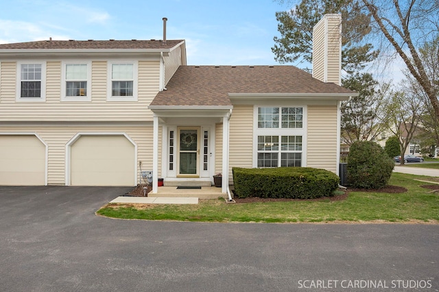 view of front of property featuring a chimney, aphalt driveway, a shingled roof, and a garage