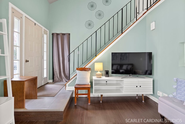 foyer featuring baseboards, wood finished floors, a towering ceiling, and stairs
