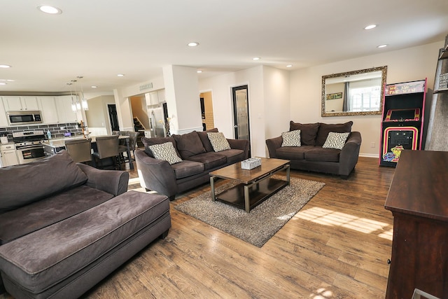 living area featuring recessed lighting, wood finished floors, and stairway