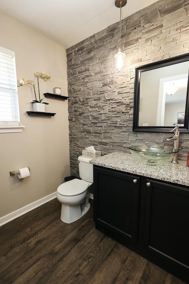bathroom featuring toilet, baseboards, wood finished floors, and vanity