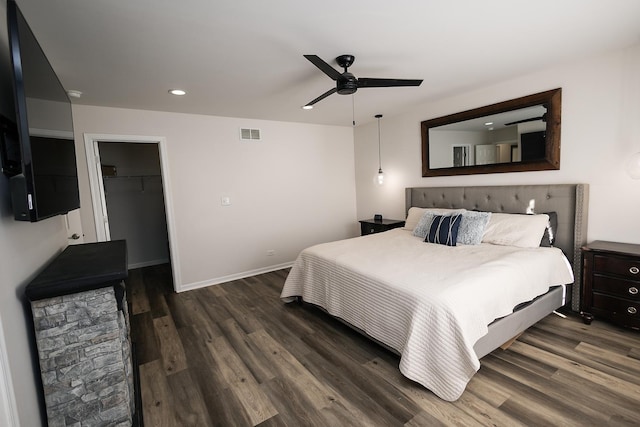 bedroom with visible vents, wood finished floors, baseboards, a walk in closet, and recessed lighting