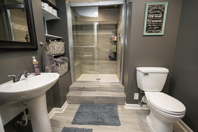 full bathroom with baseboards, a stall shower, and toilet