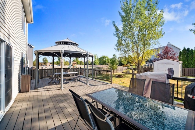 wooden deck with outdoor dining area, a fenced backyard, a shed, a gazebo, and an outbuilding
