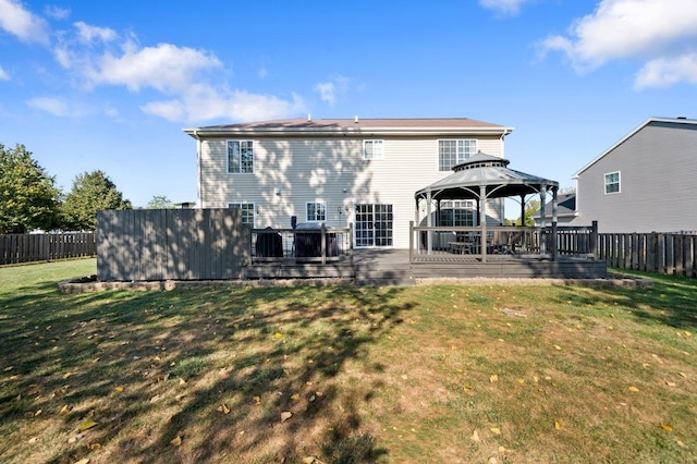 rear view of property featuring a lawn, a gazebo, a wooden deck, and a fenced backyard