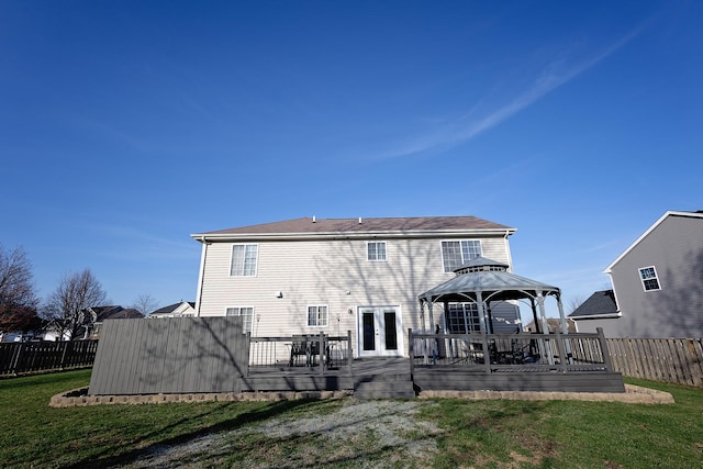 back of property featuring french doors, a lawn, a wooden deck, a gazebo, and fence
