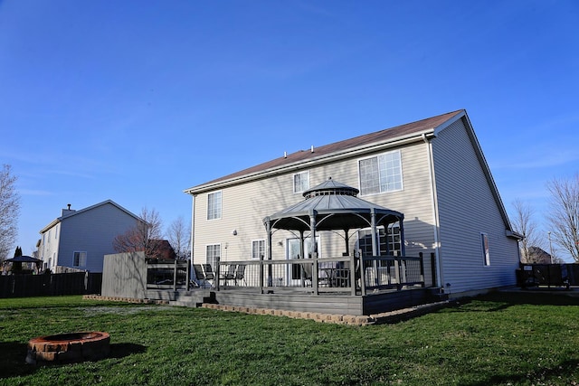 back of property featuring a gazebo, a yard, a fire pit, and a deck