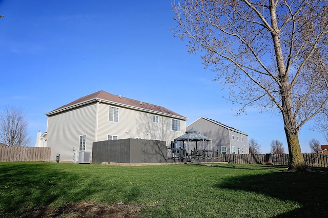 back of property with a fenced backyard, a yard, a gazebo, and cooling unit